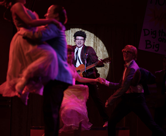A person playing the guitar on the Alhambra Theatre stage.